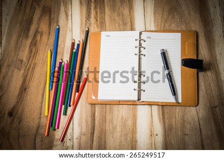 notebook with pen and pastel on wooden table