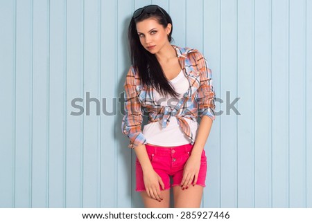 Summer, fashion and people concept - bright stylish pretty brunette in shirt posing in sunglasses against colorful wall background in the city, beautiful young girl smiles sweetly, copy space, street