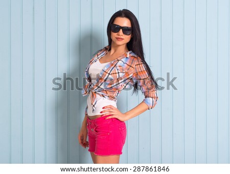 Summer, fashion and people concept - pretty brunette in shirt posing in sunglasses against colorful wall background in the city, beautiful young girl smiles sweetly, copy space, street fashion photo.