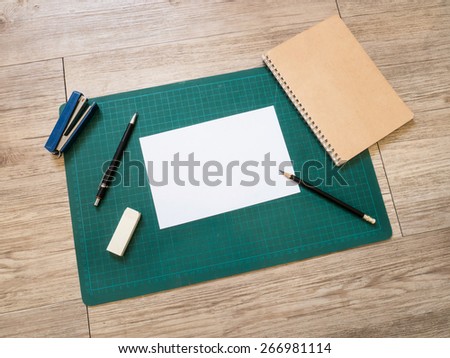 Stationery and blank white paper on cutting mat on wooden background ( White paper for text )