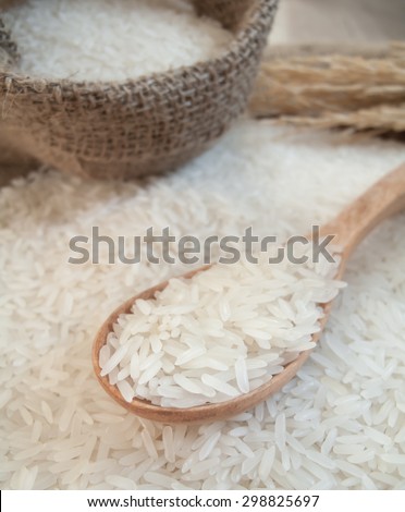 White rice on the wooden spoon and in the sack bag