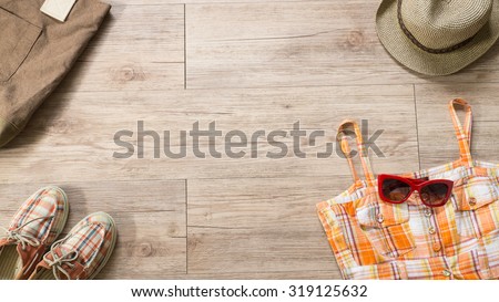 Top view of Women cloth and accessories -  Orange dress and red sunglasses , tote bag, hat  and shoe  on wooden background ( Composition and space for text )