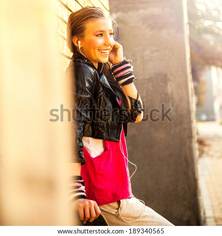 Cute young girl with earphones and skateboard, on the street