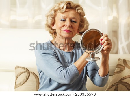 Smiling elderly woman comb and looked in the mirror.