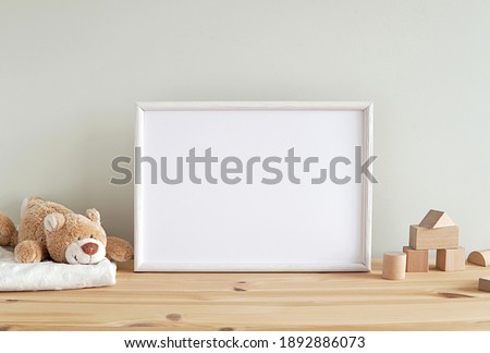 Blank horizontal frame mockup, nursery framed wall art, baby room art, empty frame for print, photo, wooden shelf, baby toys and blanket.  