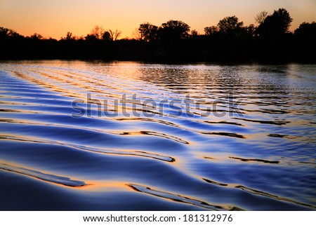 Ripples In The Wake Of A Pontoon Boat At Sunset On Whitewood Lake, Part Of The Huron River Chain Of Lakes, Southeastern Michigan, USA