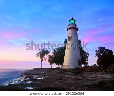 The Marblehead Lighthouse Radiates It\'s Green Light As The Sun Warms The Eastern Sky Initiating A Brand New Day At Marblehead Ohio On Lake Erie, USA