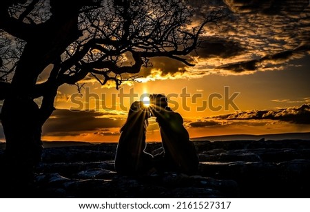 Photo of Silhouette of a couple in love kissing at sunset. Couple in love kissing at sunset. Falling in love at sunset. Romantic dating at sunset
