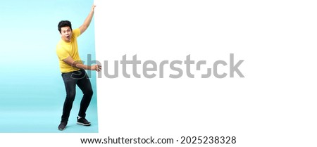 Full body Asian man Happy smiling Shock and surprise face for pulling big white board, on blue background in studio With copy space for ads. 商業照片 © 