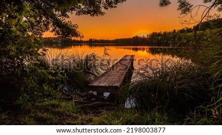 Lake pier in the early morning at dawn. Lakeview at dawn in early morning. Early morning sunrise over forest lake. Lake per at dawn Foto d'archivio © 