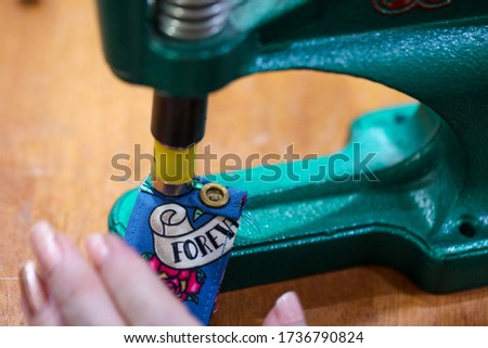 A worker using a snap machine to create press studs or snaps on garments.  ストックフォト © 