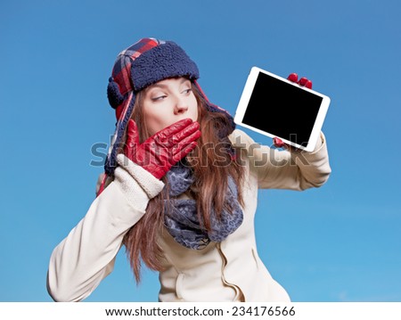 christmas, x-mas, electronics, gadget concept - smiling woman in winter clothes with tablet pc on blue background