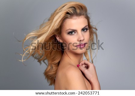 Beautiful young woman with blonde hair. Pretty model poses at studio.