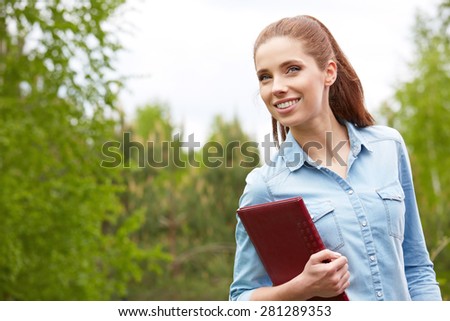 Pretty young woman student in the park. Beauty smiling girl outside.