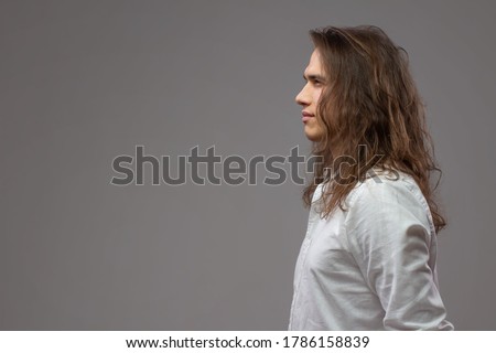 Similar – Image, Stock Photo Long haired young handsome man on a black background with a light illuminating his face, with a flirtatious expression for the camera showing a slight smile