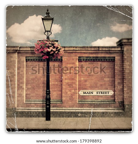 An Old Vintage Photograph of a Red Brick Wall with an Old Street Light and Main Street Sign