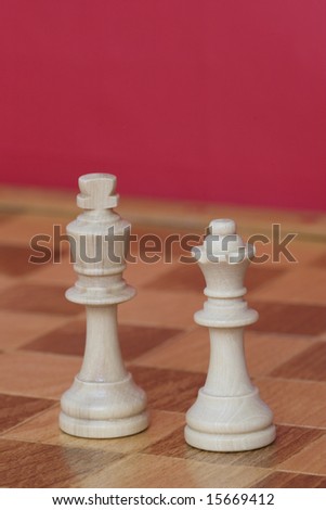 White King and Queen from a game of chess on a chess board against a red background