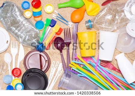 Disposable single use plastic objects such as bottles, cups, forks, spoons and drinking straws that cause pollution of the environment, especially oceans. Top view on sand Foto stock © 