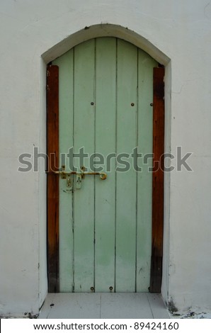 Green door with wooden panels and fancy door knob in Singapore