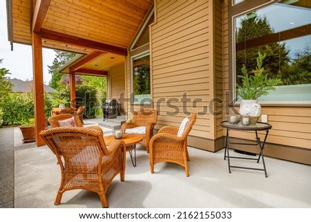 Craftsman home cedar siding solid wood pillars patio veranda deck grassy green yard blue sky and landscaping Foto stock © 