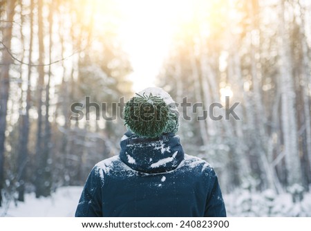 young man in a winter outfit standing in the middle of a winter snowy forest