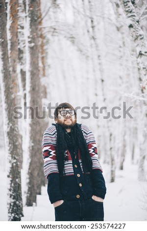 funny geeky hipster man making funny faces in the snowy winter forest