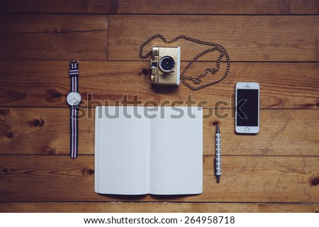 Paper notebook,watches,lomography film camera, pen and a touchscreen smartphone on the old wooden table background