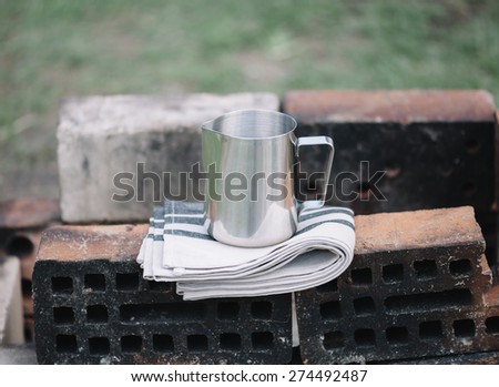 Frothing milk pitcher on the cloth napkin on the old red bricks