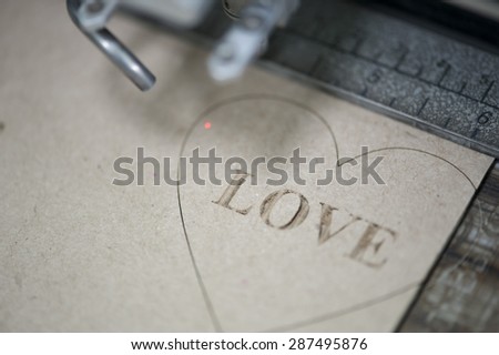 Industrial laser engraving word love on a paperboard