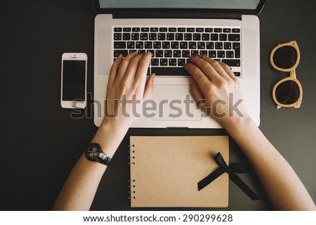 Cropped image of a young woman, wearing watches on her hand, working on her laptop in a coffee shop, rear view of business woman hands busy using laptop at office desk