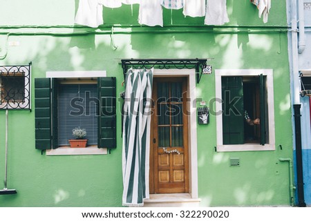 Beautiful house facade on Burano island, north Italy. Colorful green house wall with a door and some windows