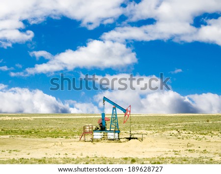 pumping oil from an oil well on the background of sky with clouds