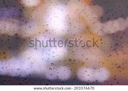 Drops of rain on window with bokeh lights background