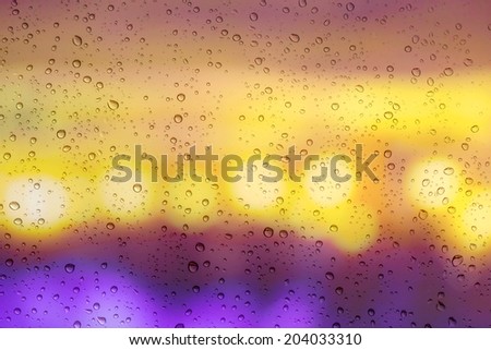 Drops of rain on window with bokeh lights background