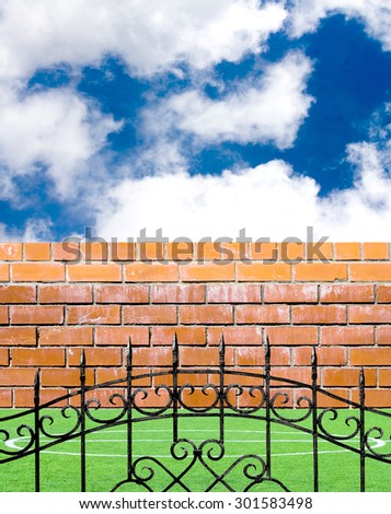 Old brick wall, metal fence and green grass on a sky background