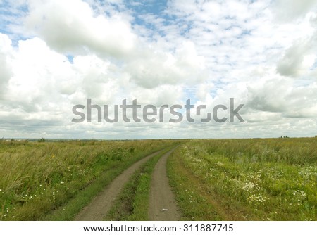 field road on a background cloudy sky