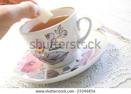 Hand putting sugar in cup of tea. Concept for tea shop or web site