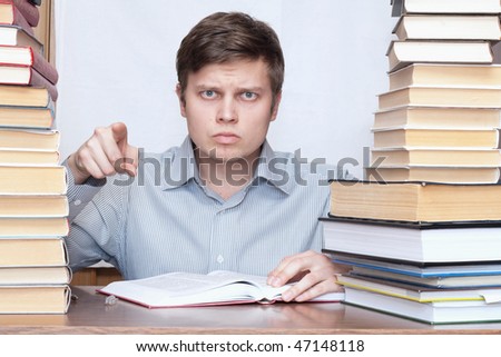 Young serious man show finger to you between books