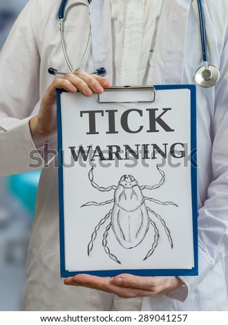 Doctor holds blue clipboard with tick warning