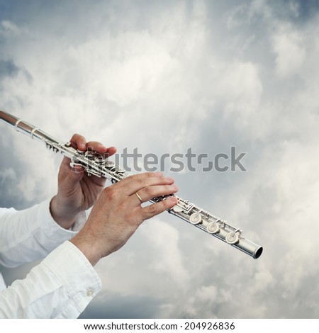musician playing flute on a neutral background