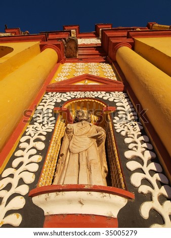 Close up of statue on old, brightly painted colonial church in the town center of San Cristobal de las Casas, Chiapas, Mexico.