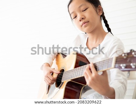 Pretty girl child and acoustic guitar isolated on white background. Kid guitarist put fingers on fingerboard of string instrument playing 5th fret songs. Selective focus on right-hand fingerpicking. Stock foto © 