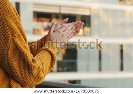 Stock photo of a girl's hands applauding from her balcony to support those fighting coronavirus