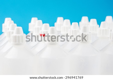 white translucent bottles used in homeopathy with one specific focused bottle on blue and blurred bottles background