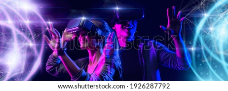 Teenager having fun play VR virtual reality glasses metaverse sport game 3D cyber space futuristic neon colorful background, future digital technology game and entertainment