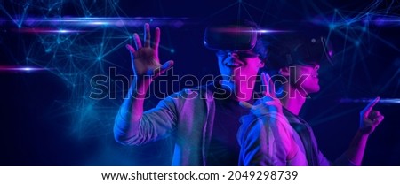 Teenager having fun play metaverse VR virtual reality glasses Esport game futuristic neon colorful background, future digital technology NFT game and entertainment