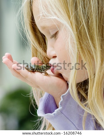 Happy young girl kissing a frog