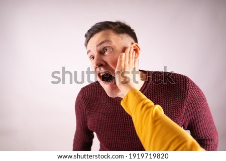 Crop person slapping scared man in face. Emotional male getting slapped in face while shouting with closed eyes in fear on white background. Stock fotó © 