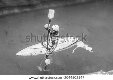 Black and white closeup photo of a tiny model person kyaking on a river Stok fotoğraf © 