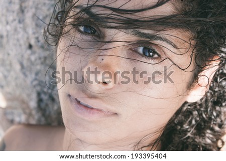 Close-up portrait of a beautiful brunette exotic young woman with wet rebel hair, looking at camera with black eyes